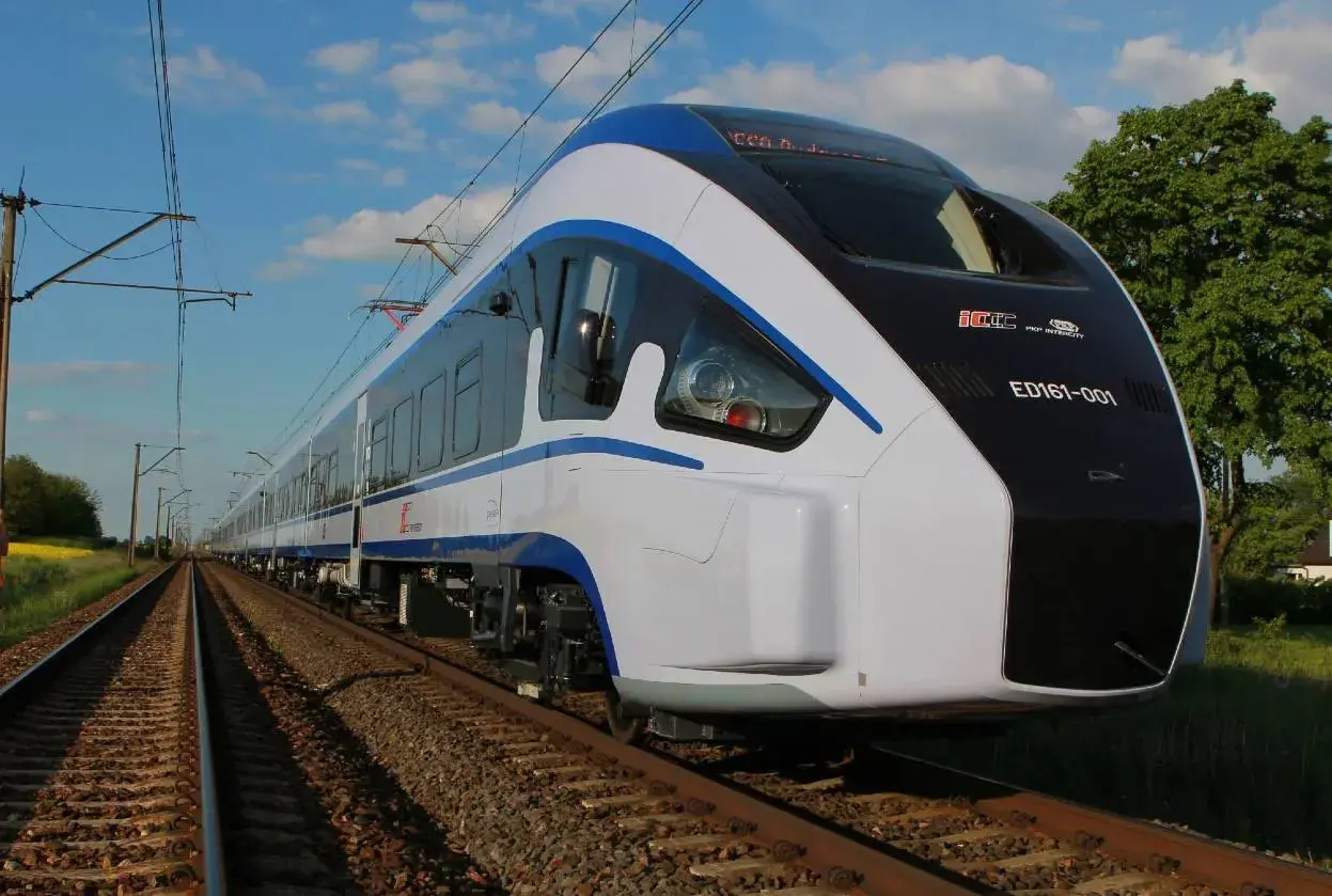Nowoczesny pociąg ED161-001, najszybszy pociąg w Polsce, mknie po torach wśród zieleni.