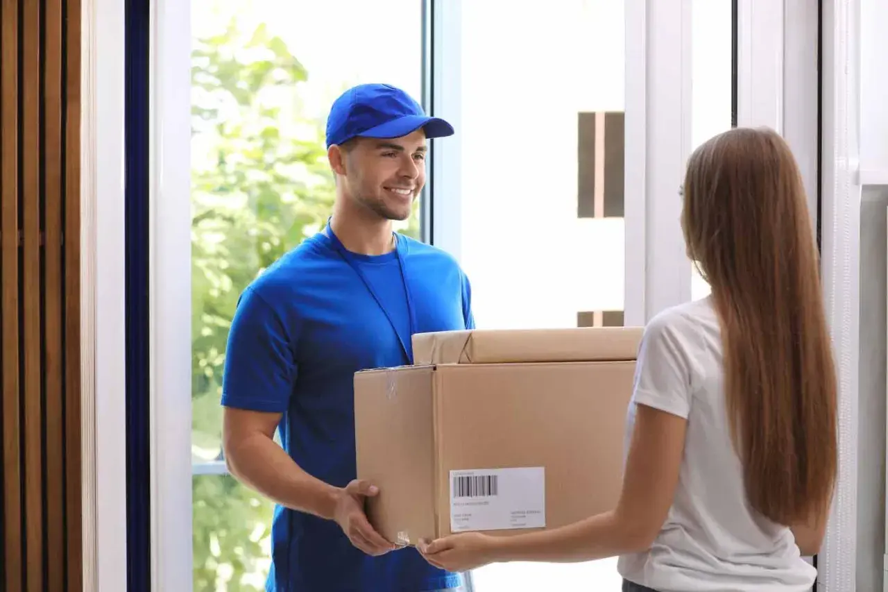 Lieferbote übergibt Frau ein Paket. Sie hofft, dass es nicht die **nicht bestellte Ware** ist, die sie schon einmal erhalten hat.
