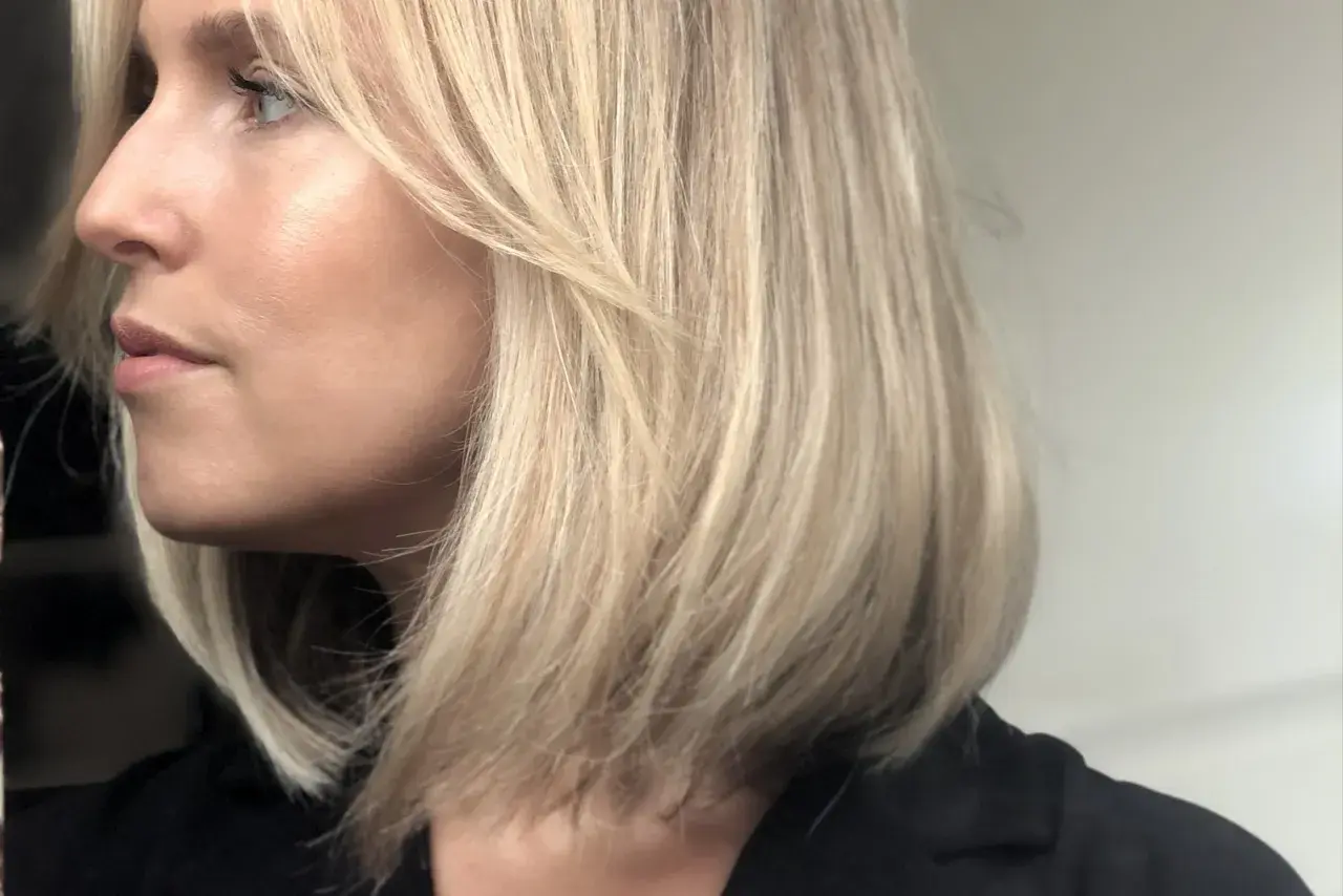 En kvinna med blont hår i en lobklippning, med en naturlig sminkning som framhäver hennes ansiktsdrag. Perfekt för smink tips.