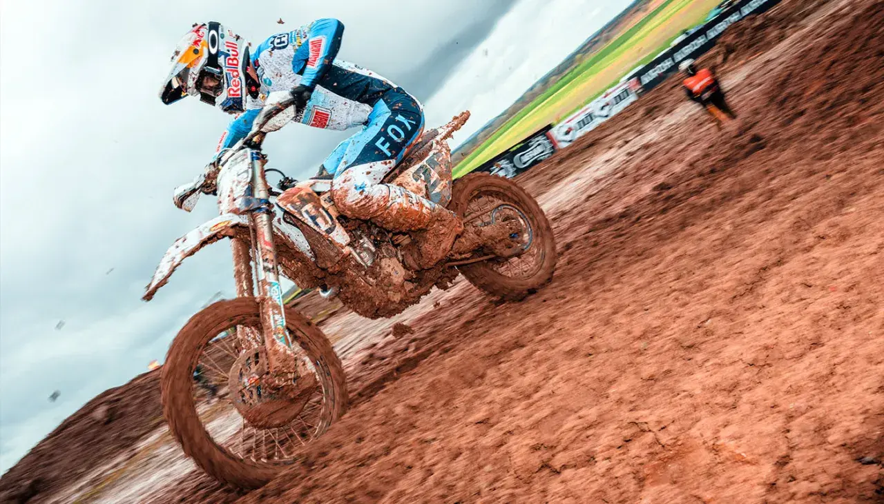 Motocyklista w błocie podczas wyścigu motocrossowego.