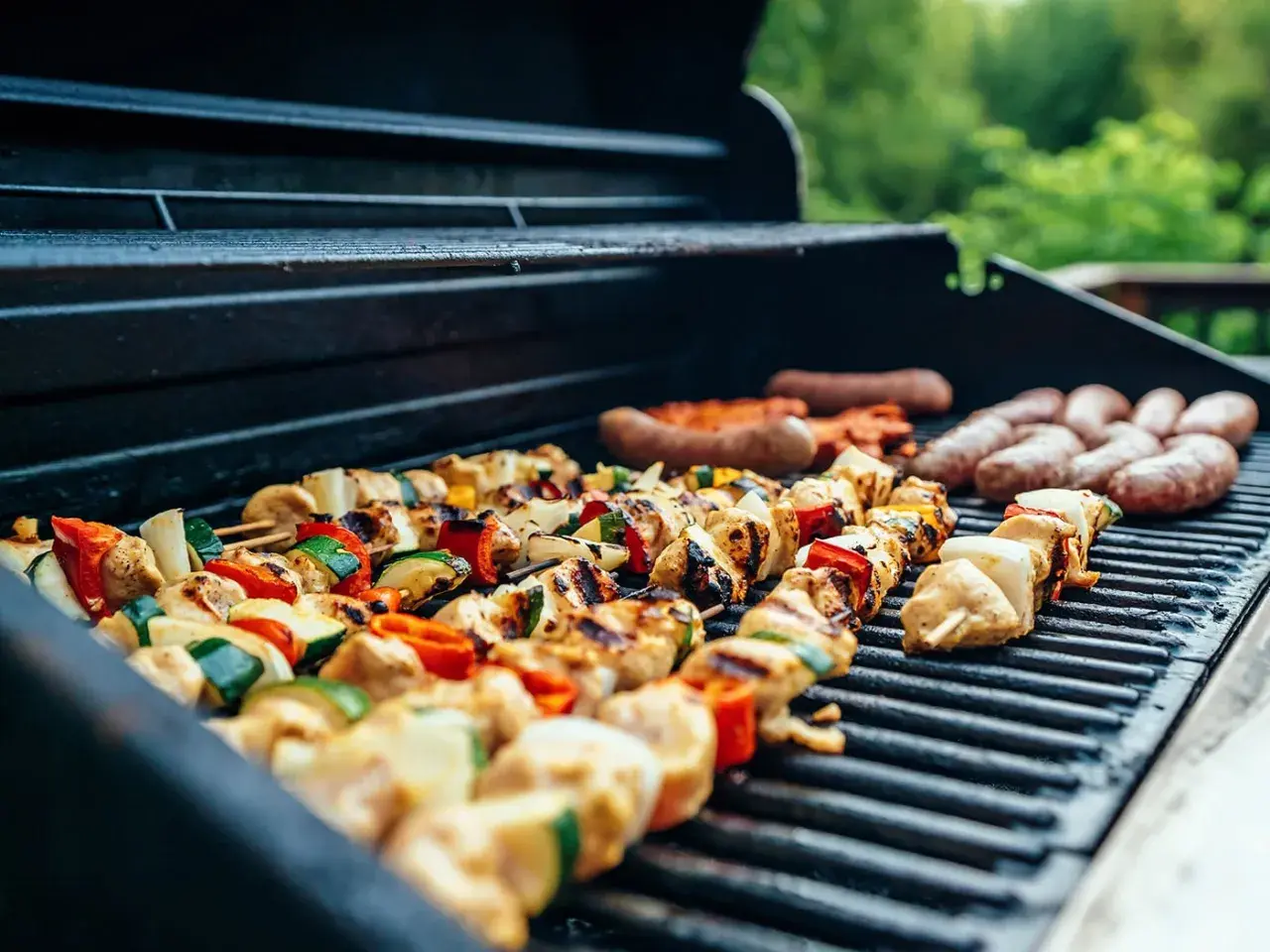 Brochettes de poulet et légumes, saucisses en train de cuire sur un barbecue à gaz.