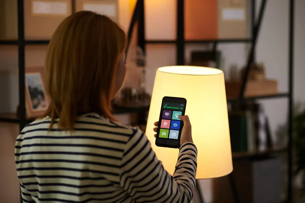 Kobieta steruje domem przez aplikację na telefonie. To smart life po polsku, wygoda i nowoczesność w zasięgu ręki.