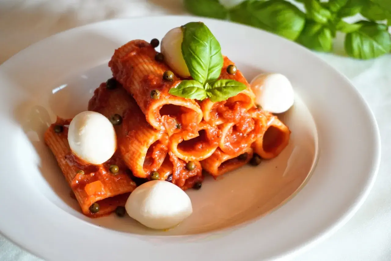 Rigatoni z aromatycznym, czerwonym pesto, kulkami mozzarelli i świeżą bazylią. Pyszne danie, które zachwyca smakiem.