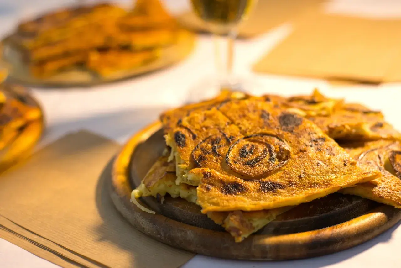 Farinata dorata, un classico per sapere cosa mangiare a Pisa. Croccante fuori, morbida dentro, con cipolle caramellate.
