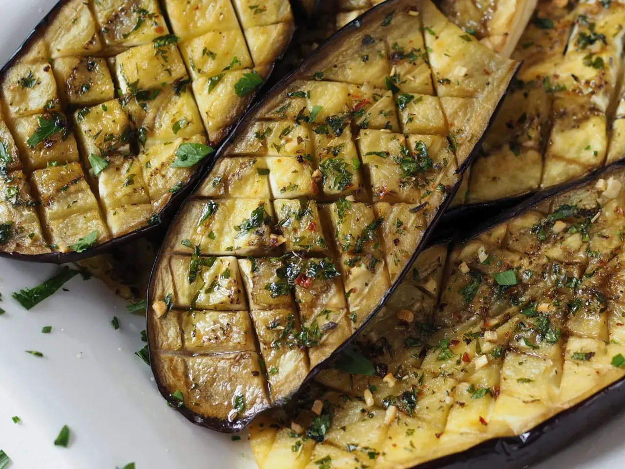 Gegrillte Auberginenhälften, mit Kräutern und Knoblauch gewürzt, bereit zum Servieren. Ein köstliches Gericht, das die Aromen des Ofens einfängt.