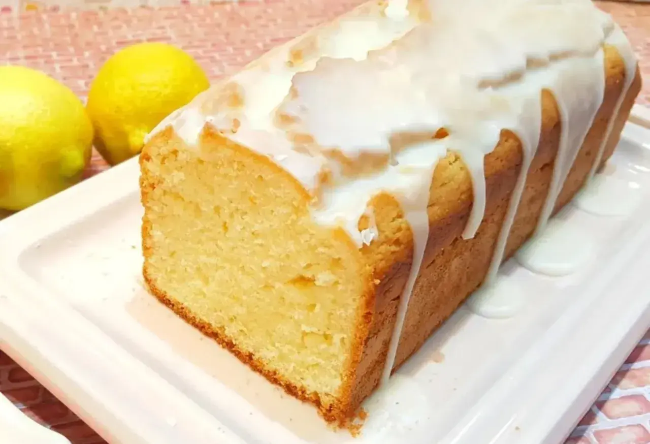 Budín de limón casero con glaseado blanco, acompañado de dos limones frescos. ¡Perfecto para la merienda!