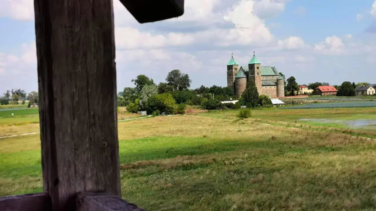 Wnętrze kolegiaty z rzędami drewnianych ławek i witrażami w oknach.