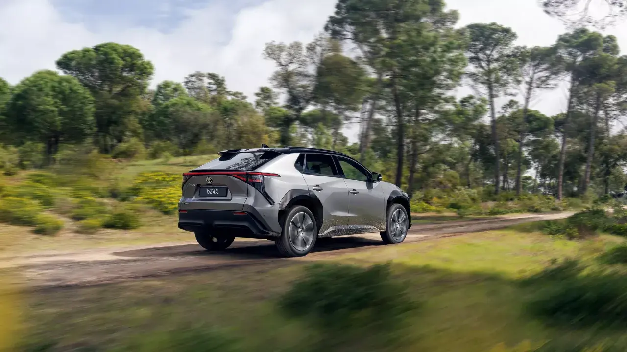 Srebrny Toyota bz4x cena jest atrakcyjna, gdy jedzie po leśnej drodze.