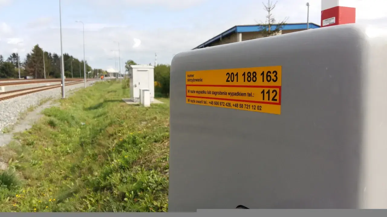 Żółta naklejka plk. z numerem skrzyżowania 201 188 163 i numerem alarmowym 112.