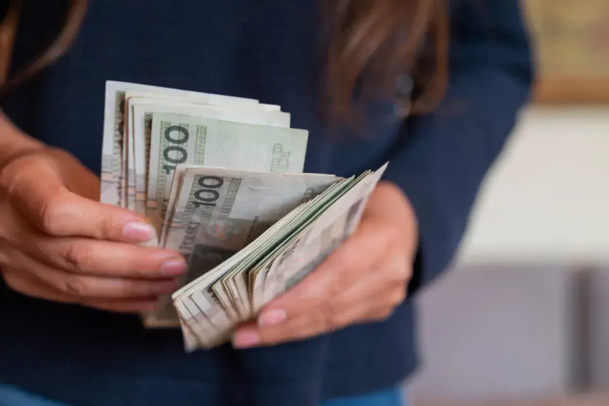Dłonie liczą banknoty 100 zł. To może być darowizna od rodziców na nowy cel.