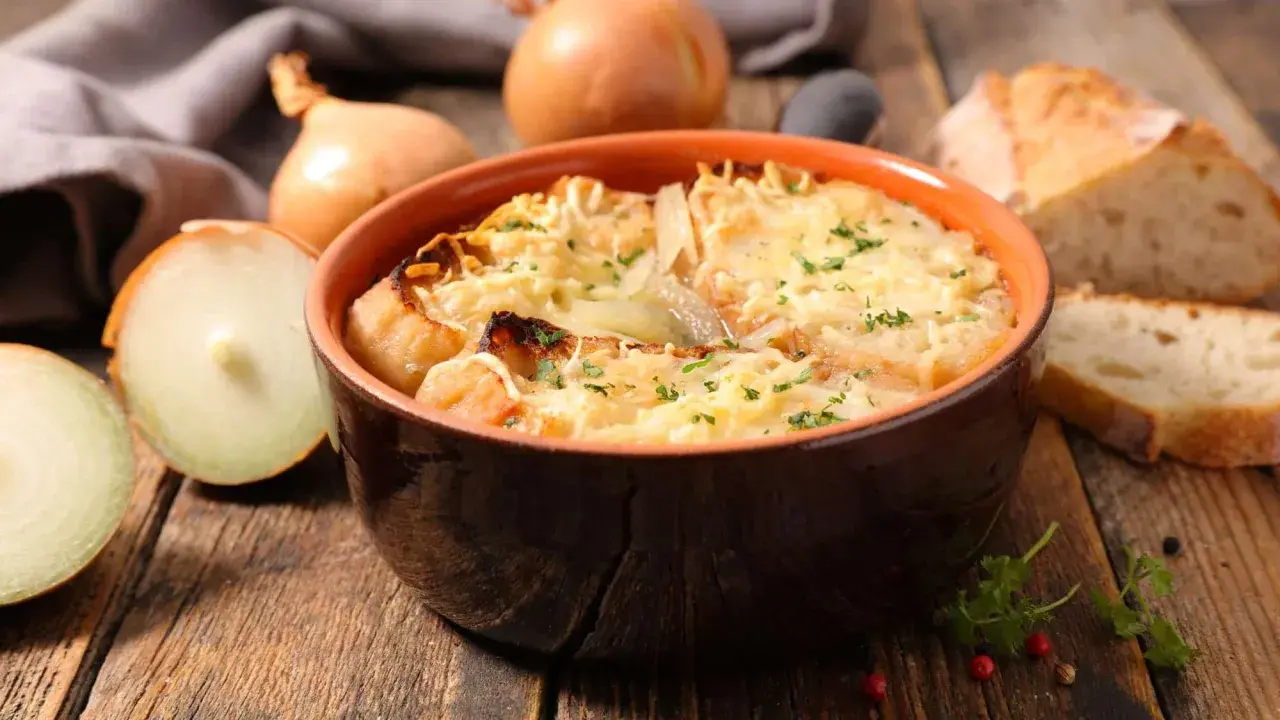 Un bol de soupe à l'oignon gratinée, prêt à être dégusté. Une recette réconfortante avec du pain et du fromage fondu.