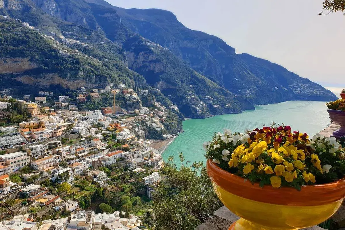 Colorful flowers bloom overlooking Positano, a stunning town cascading down the cliffs. This view offers inspiration for where to stay in Amalfi Coast.