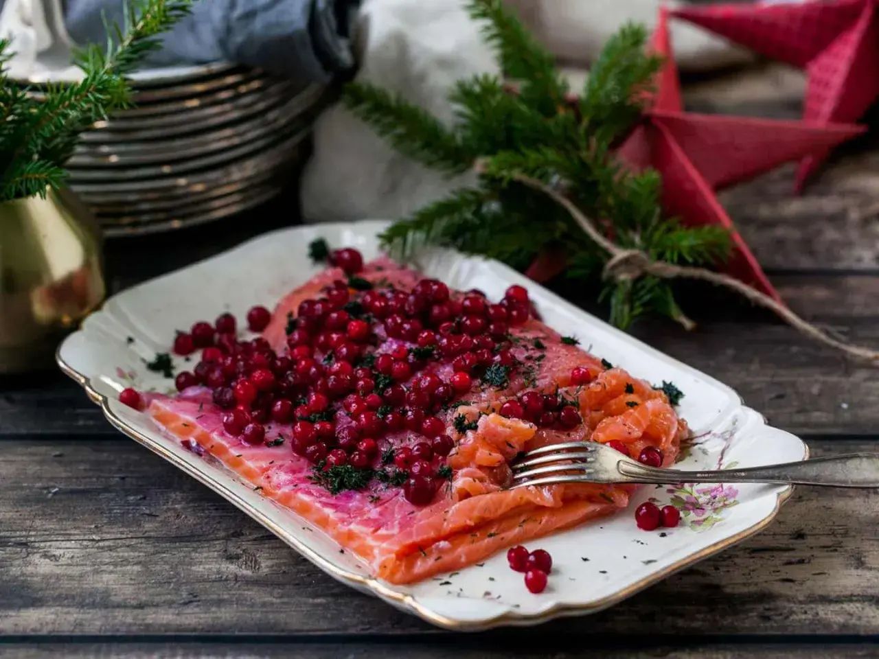 Apelsingravad lax med lingon och dill på ett vackert fat, redo för julbordet.