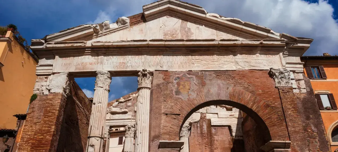 Antico portico d'Ottavia a Roma, con iscrizioni latine e resti di affreschi su mattoni antichi.