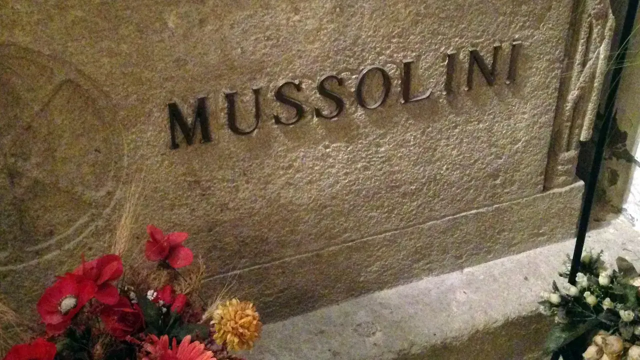 Grabstein mit der Inschrift "MUSSOLINI" und Blumen. Hier ist das Grab von Mussolini.