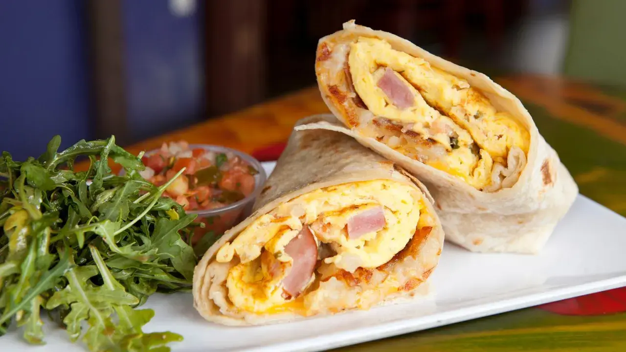 Pyszny omlet z tortillą, jajecznica, szynka i ziemniaki zawinięte w placek. Obok sałatka i salsa.