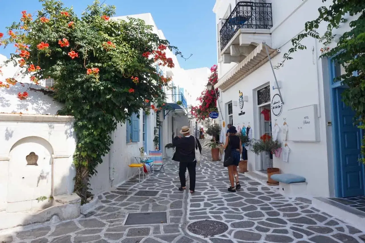 Ein malerischer Gang auf der Insel Paros, Griechenland, mit blühenden Bougainvillea und weiß getünchten Häusern.