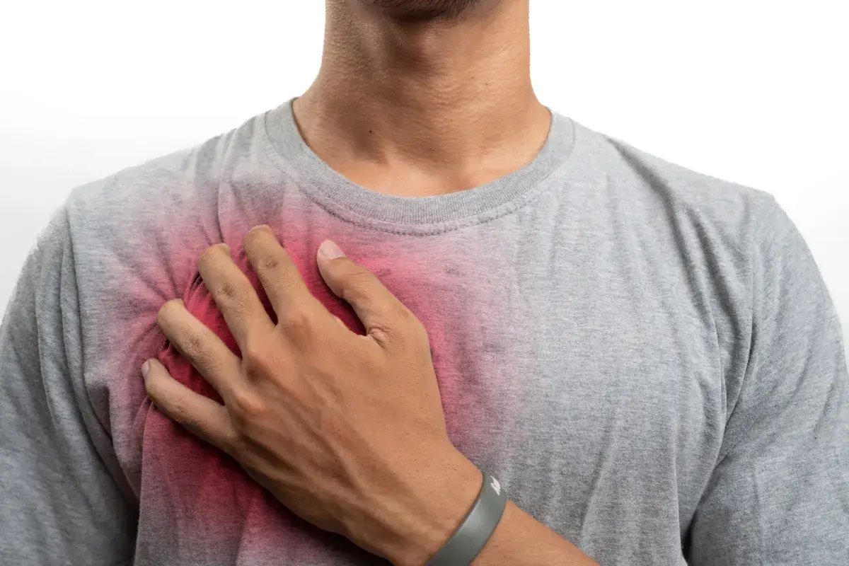Uomo con mano sul petto, evidenziando un'area arrossata che suggerisce prurito al petto uomo.