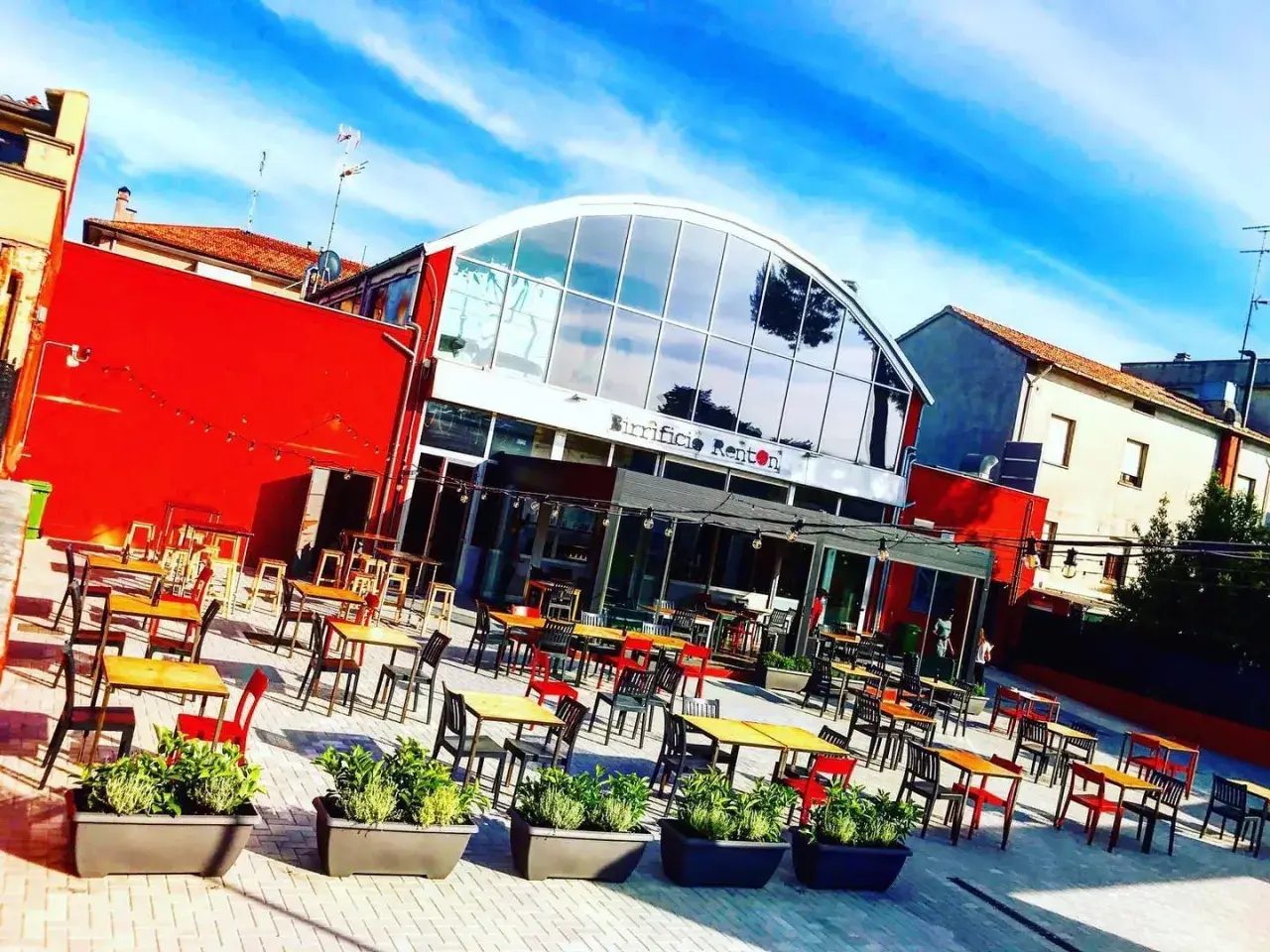 Birrificio Renton, una moderna hilltop brewery con tavoli all'aperto sotto un cielo azzurro.