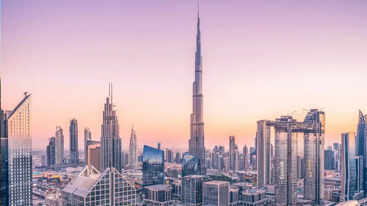 Widok panoramy Dubaju z Burdż Chalifą na pierwszym planie, w blasku zachodzącego słońca.