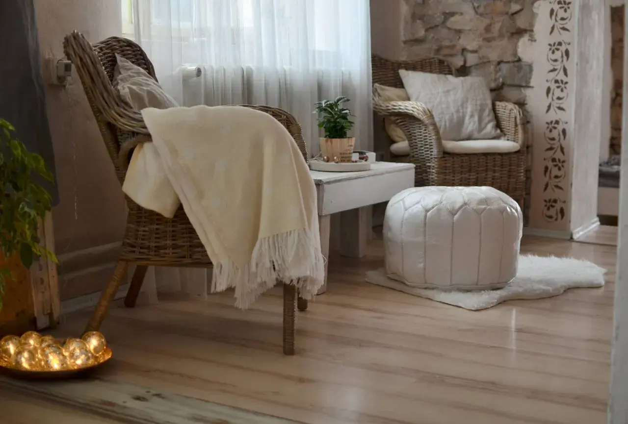 Gemütliche **hygge einrichtung**: Korbstühle, ein weicher Überwurf und ein weißer Pouf laden zum Entspannen ein.