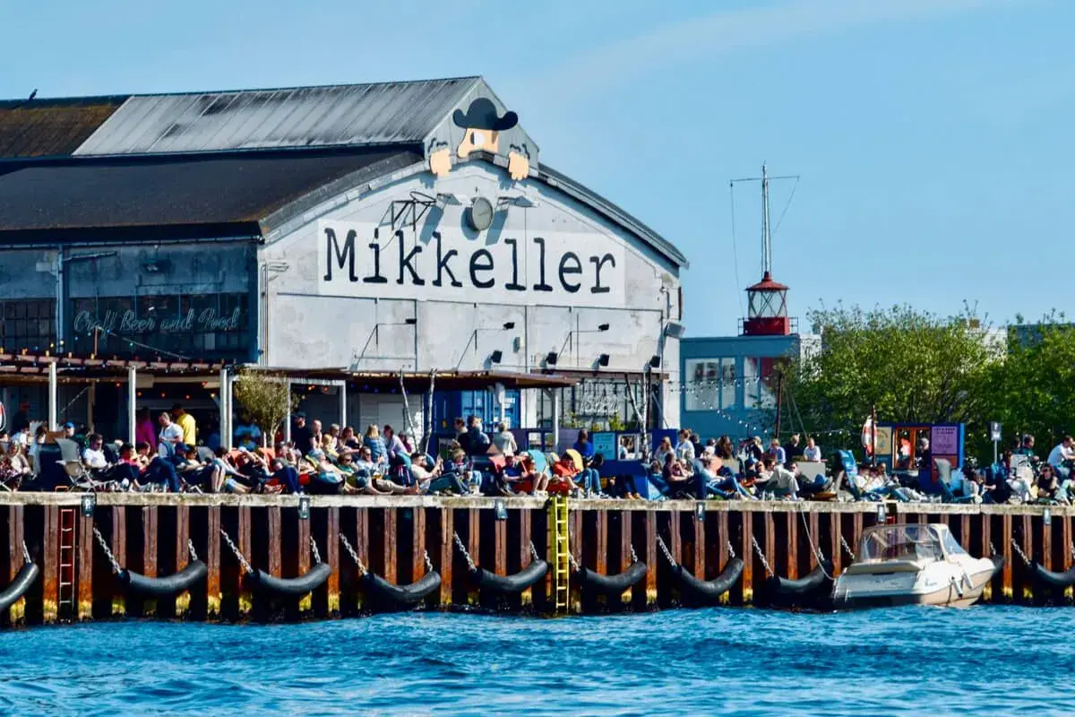 Menschen genießen das Kopenhagen Essen und Craft Beer am Kai vor dem Mikkeller Gebäude.