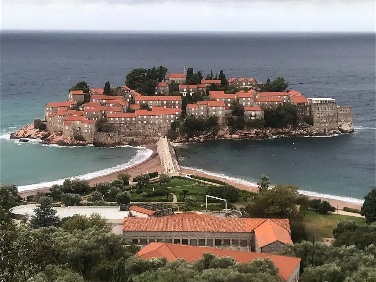 Sveti Stefan, en pittoresk ö med stenhus och röda tak, förbunden med fastlandet via en smal landremsa.
