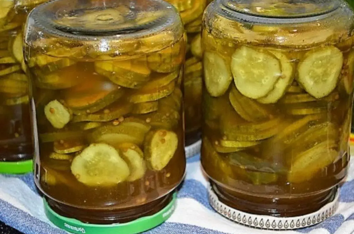 Słoiki pełne plasterków ogórków w zalewie z przyprawami, gotowe do podania jako dodatek do dań. Te ogórki w curry z pewnością dodadzą smaku!
