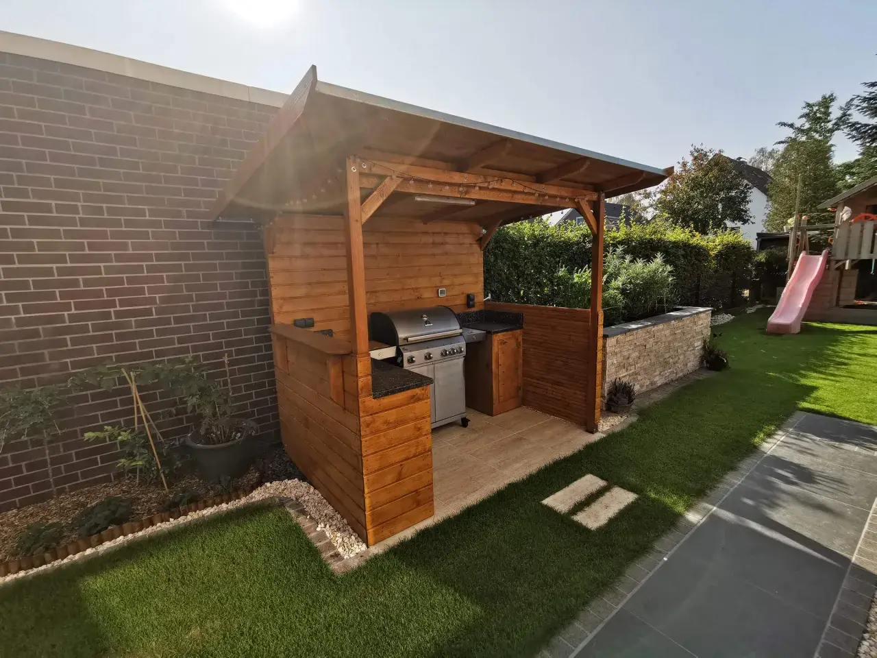 Ein schöner Grillunterstand, den man selber bauen kann, mit Grill, Arbeitsfläche und Beleuchtung.