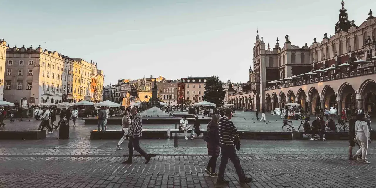 En livlig torgscen i Krakow, perfekt för din reseguide. Människor promenerar förbi historiska byggnader och marknadsstånd.