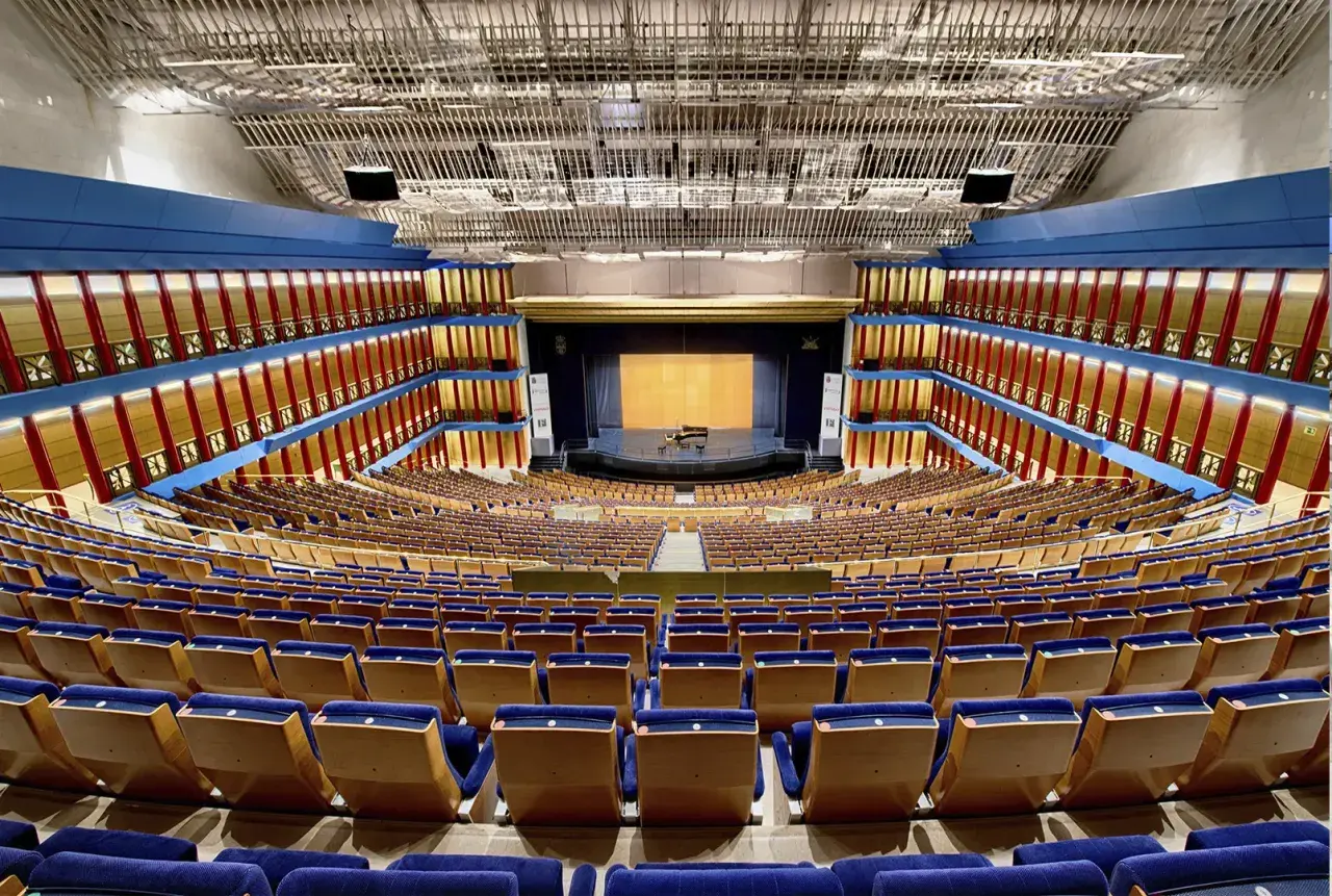 El **palacio de festivales** luce vacío, con sus butacas azules y doradas listas para recibir al público. Un piano espera en el escenario.