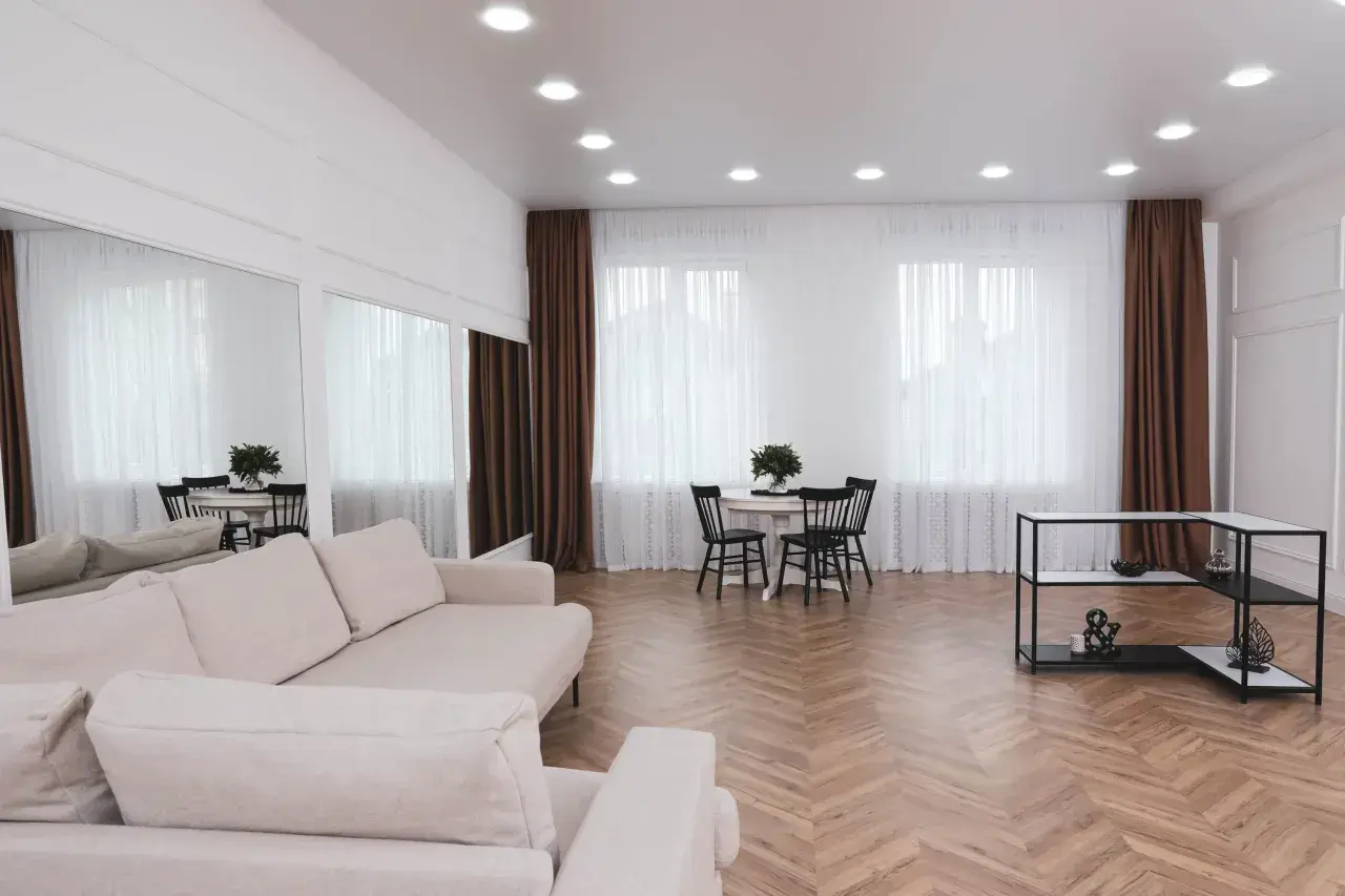 Jasne, oto propozycja:

Jasny salon z sofą, stołem i krzesłami. Sufit ozdobiony licznymi halogenami, które idealnie pokazują, jak rozmiescic halogeny w salonie, tworząc równomierne oświetlenie.