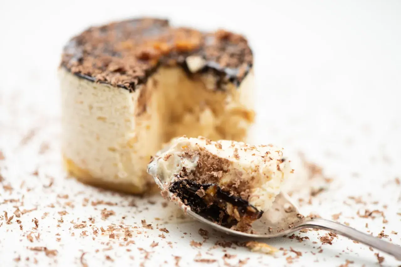 Un cucchiaino raccoglie un pezzo di delizioso parfait, con strati di crema e cioccolato, cos'è questa bontà?