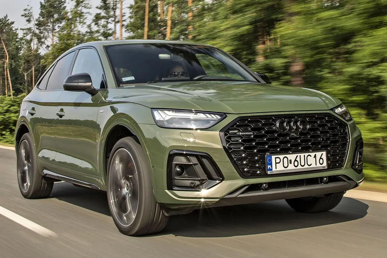 Zielony Audi Q5 Sportback w ruchu. Kierowca w okularach przeciwsłonecznych. Wiele pozytywnych audi q5 opinie o tym modelu.