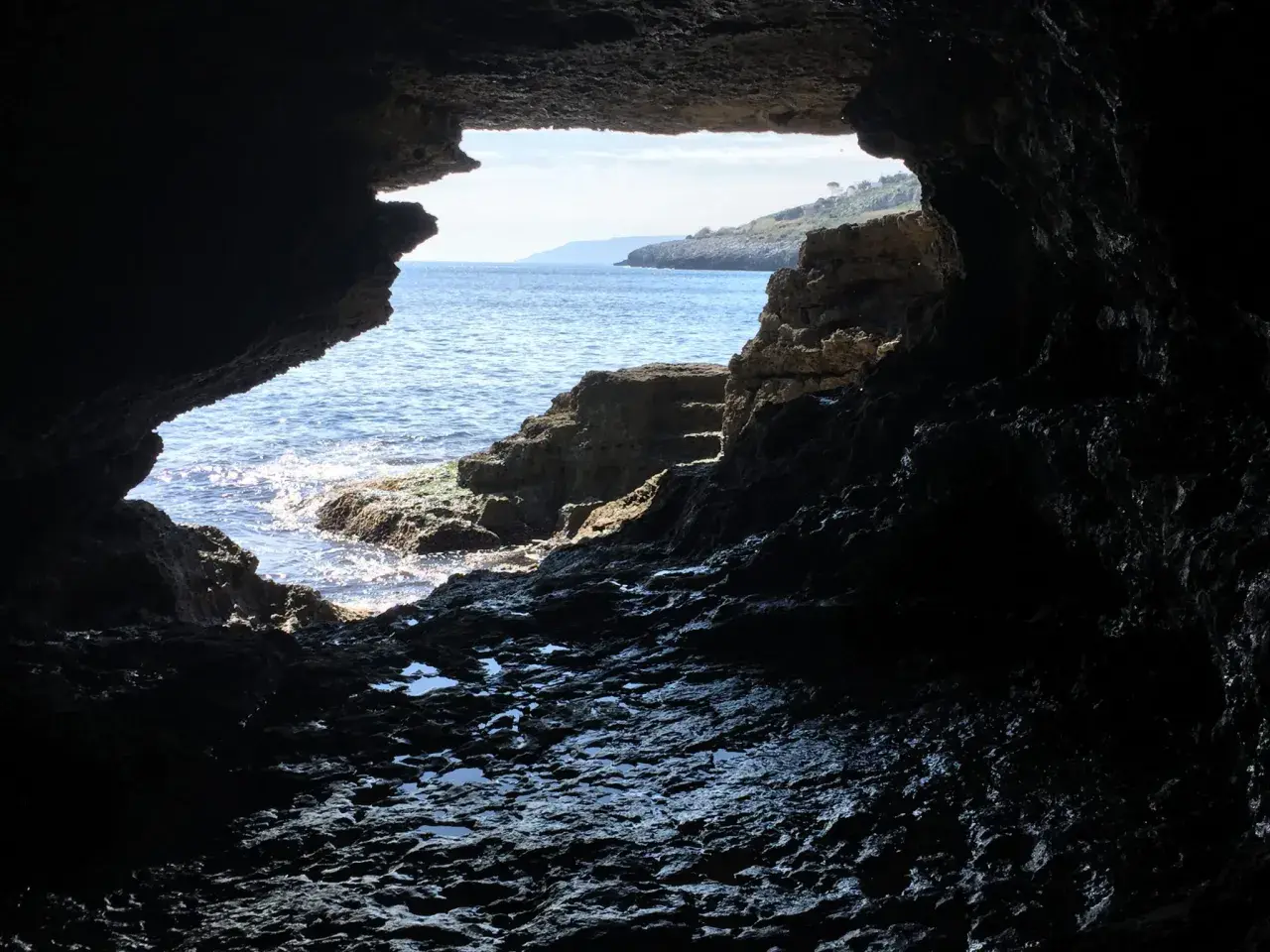 Vista dall'interno di una grotta sul mare cristallino e la costa rocciosa. La spiaggia della grotta verde è un luogo magico.