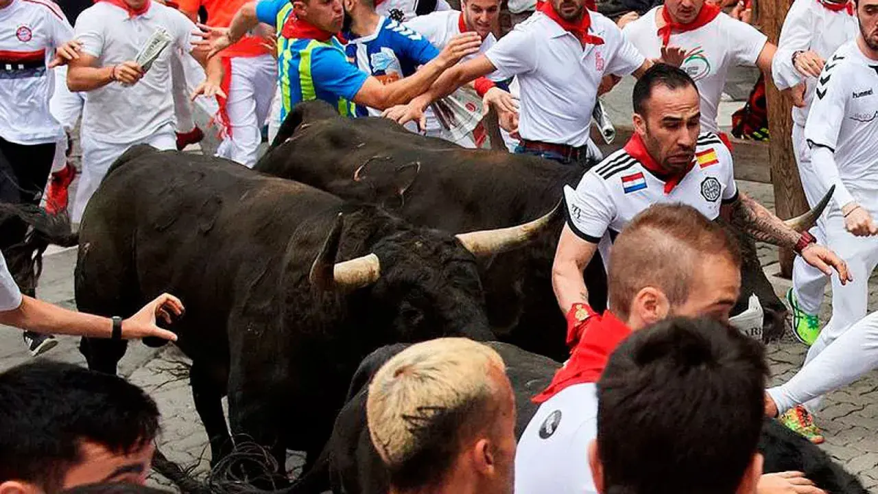 Hombres corren junto a toros negros de ganadería Guadaira.