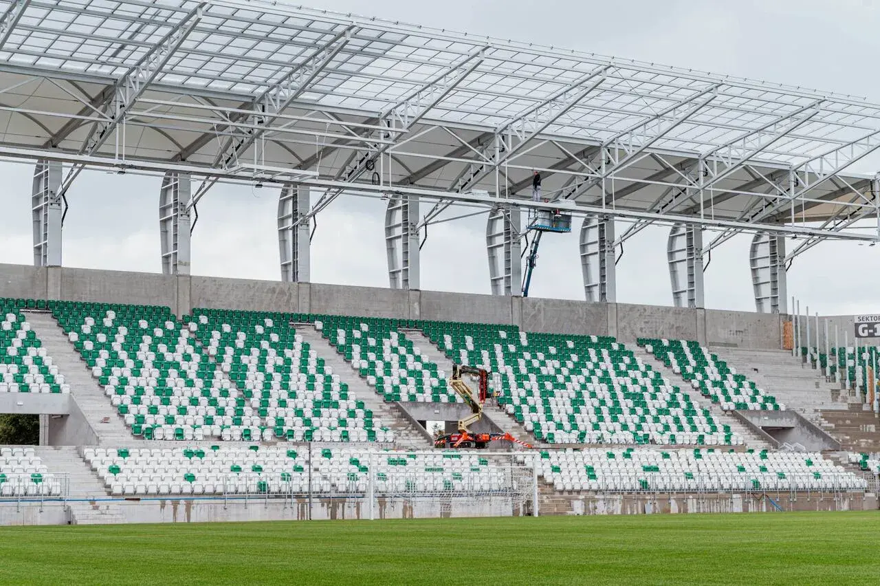 Stadion Radomiaka w budowie. Zielono-białe trybuny czekają na kibiców, a pracownicy montują dach.
