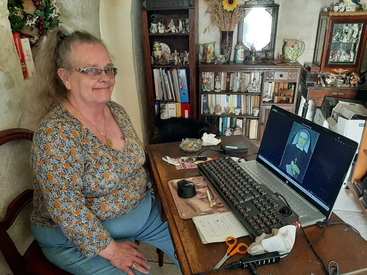 Une femme consulte des archives en Sarthe sur son ordinateur, où s'affiche le portrait d'une religieuse.
