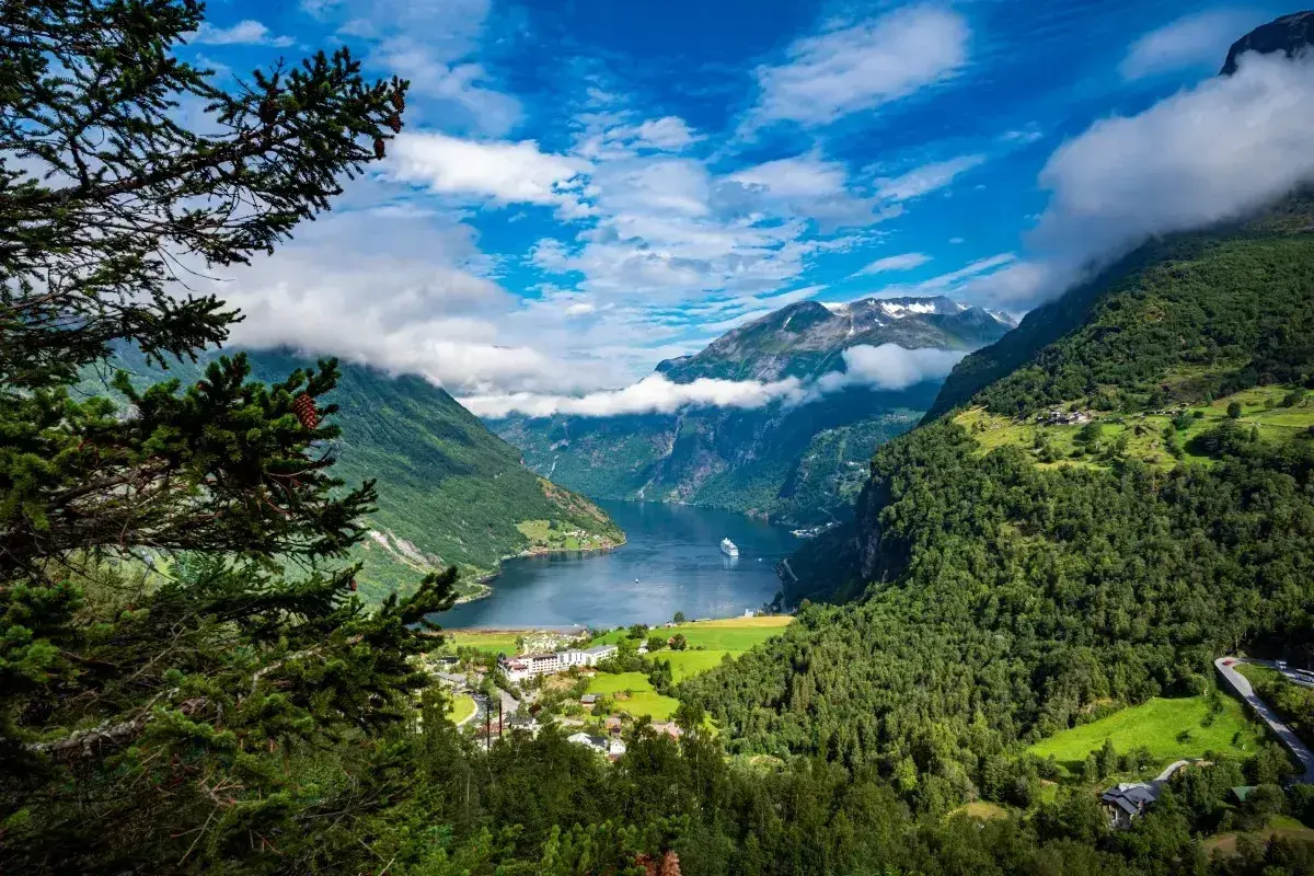 Widok na norweski fiord z górami, lasami i statkiem wycieczkowym. Idealne miejsce na wycieczkę do Norwegii.
