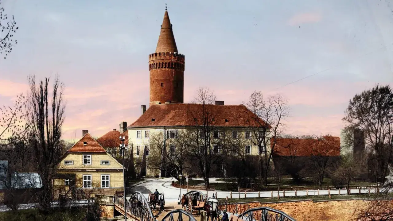 Opole stare miasto: zamek z wieżą, mosty, dorożki i kamienne domy pod różowym niebem.