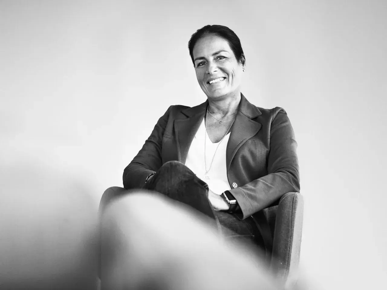 Manuela Reibold-Rolinger lächelt freundlich in die Kamera, während sie in einem Sessel sitzt. Sie trägt einen Blazer und Jeans.