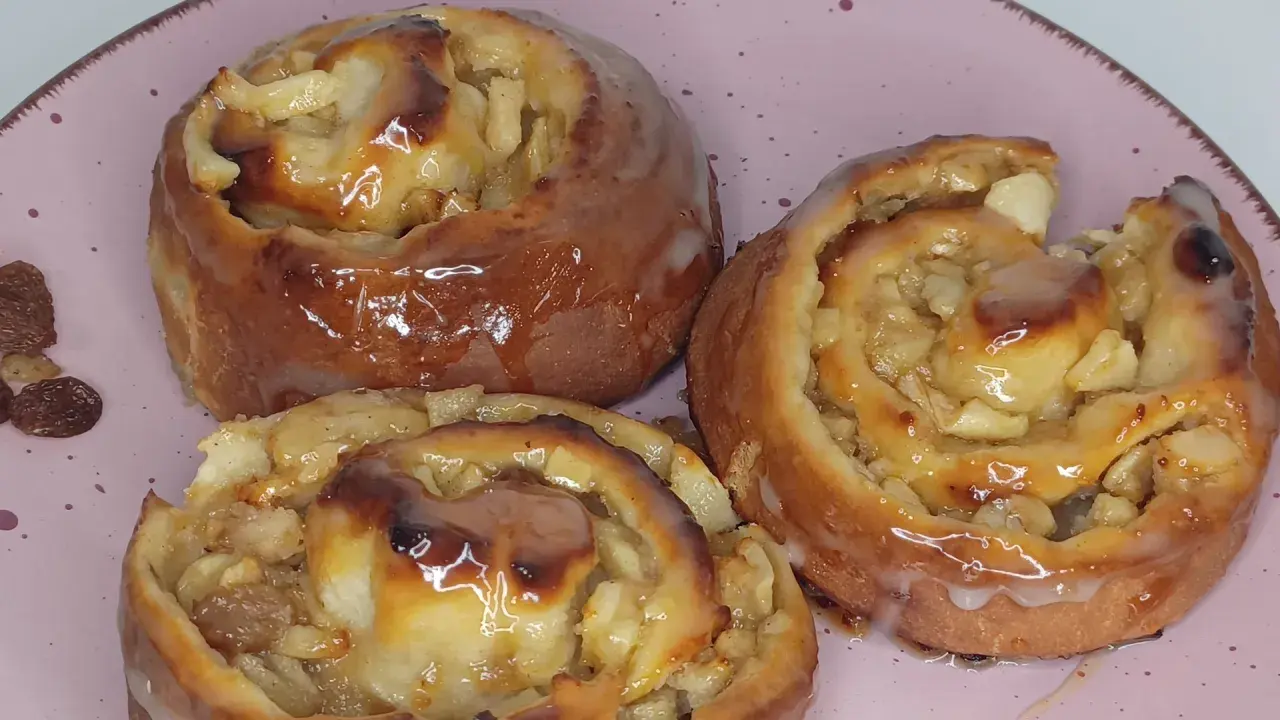 Saftige Apfelschnecken mit Glasur, ein köstliches Rezept für süße Momente. Daneben liegen ein paar Rosinen.
