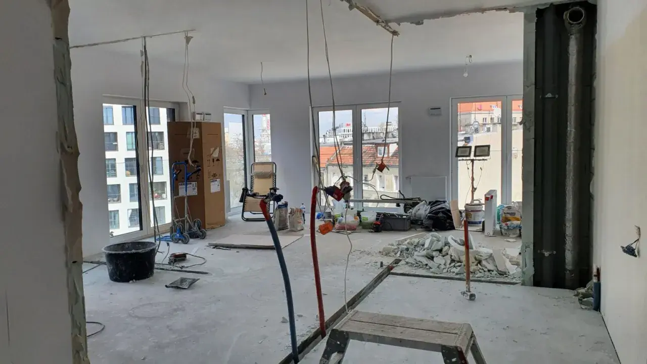 Budowa mieszkania deweloperskiego: widok wnętrza w trakcie prac remontowych, materiały budowlane, okna.