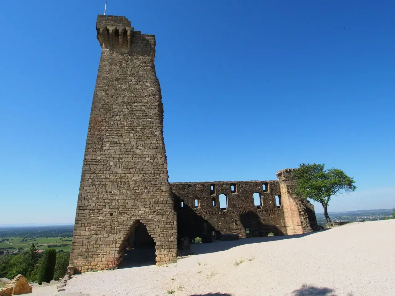 Ruinen der Burg von Châteauneuf-du-Pape, ein imposanter Turm und zerfallene Mauern unter blauem Himmel.