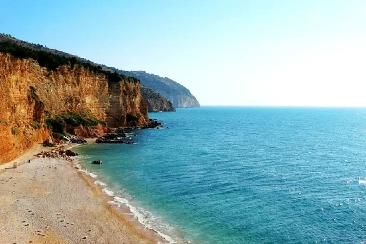 Spiaggia Punta Rossa: scogliere dorate si tuffano nel mare turchese, un angolo di paradiso incontaminato.
