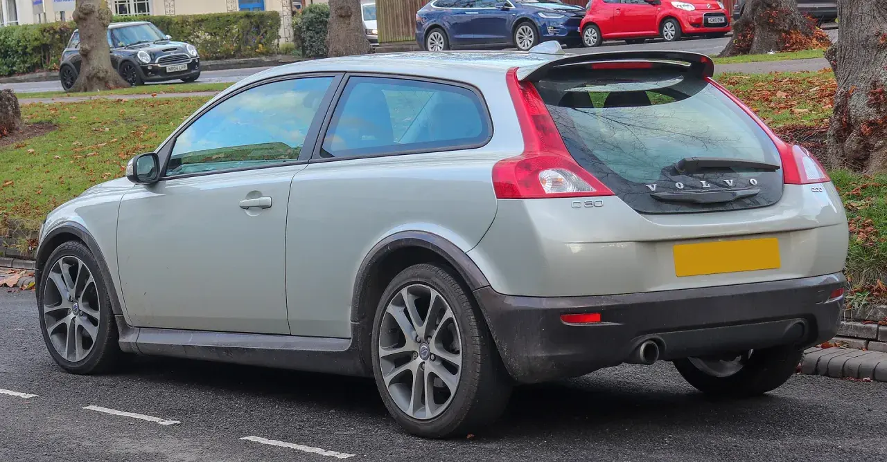 Srebrne Volvo C30 z charakterystycznym tyłem i spoilerem, zaparkowane na ulicy.