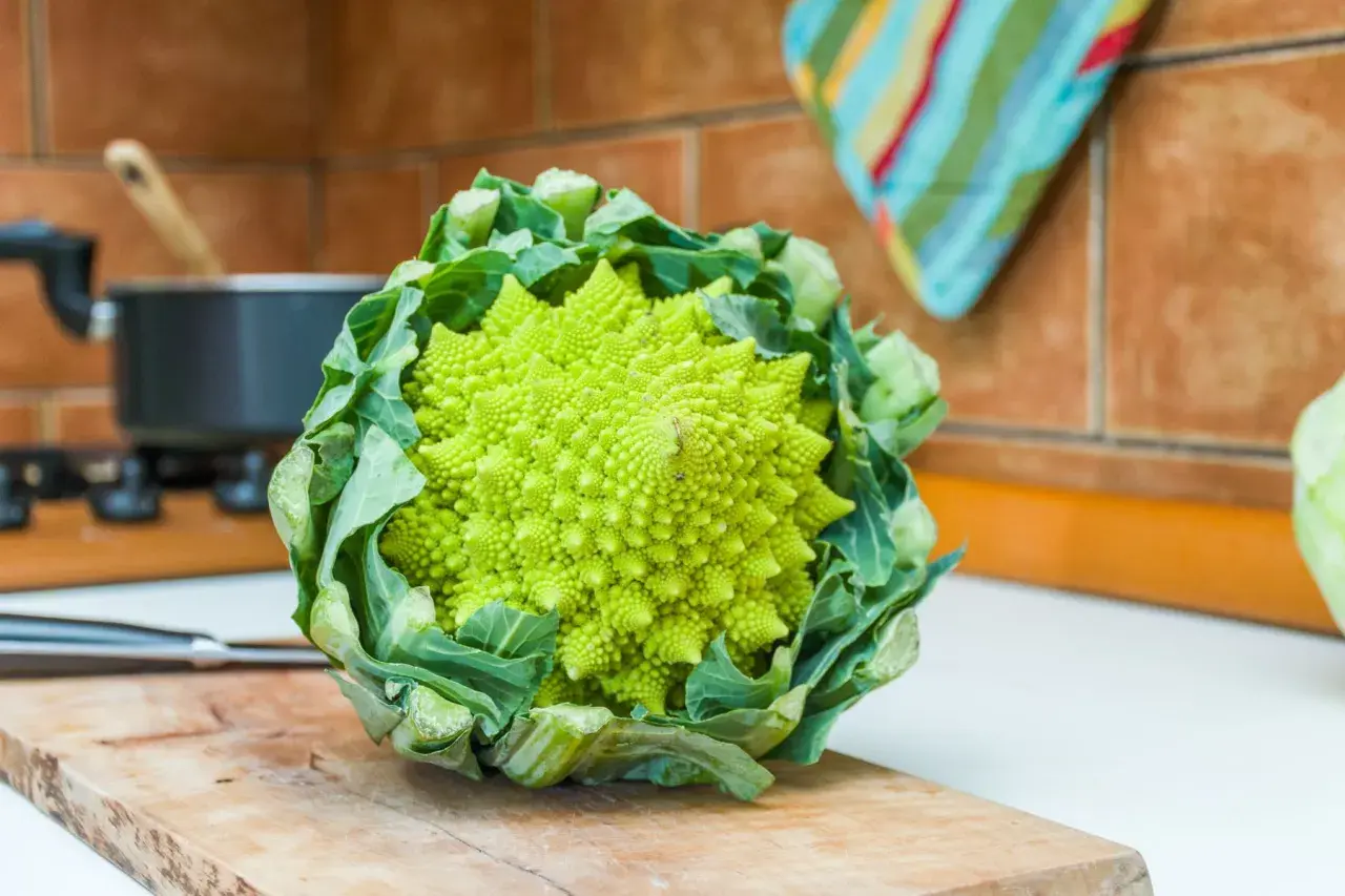 Zielony brokuł romanesco o spiralnym kształcie, gotowy do przygotowania na desce do krojenia w kuchni.