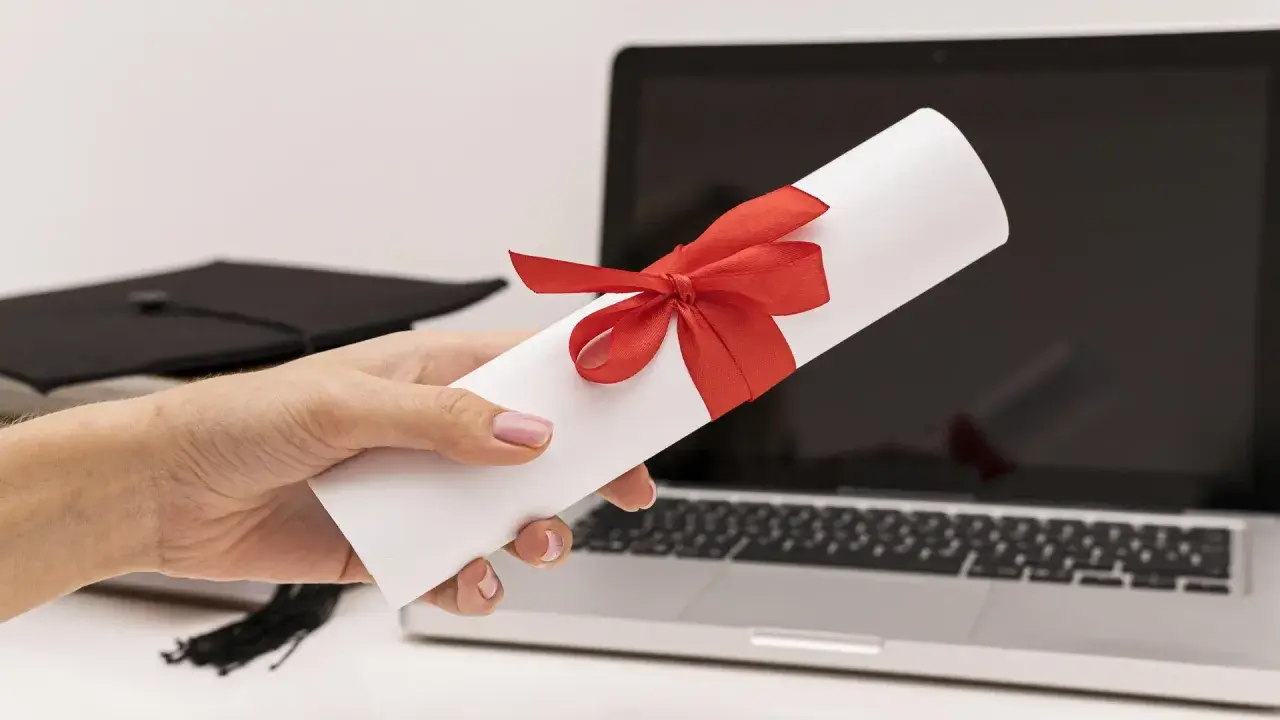 Dyplom z czerwona wstążką, czapka absolwenta i laptop. To zaproszenie dla delegacji z pracy tekst.