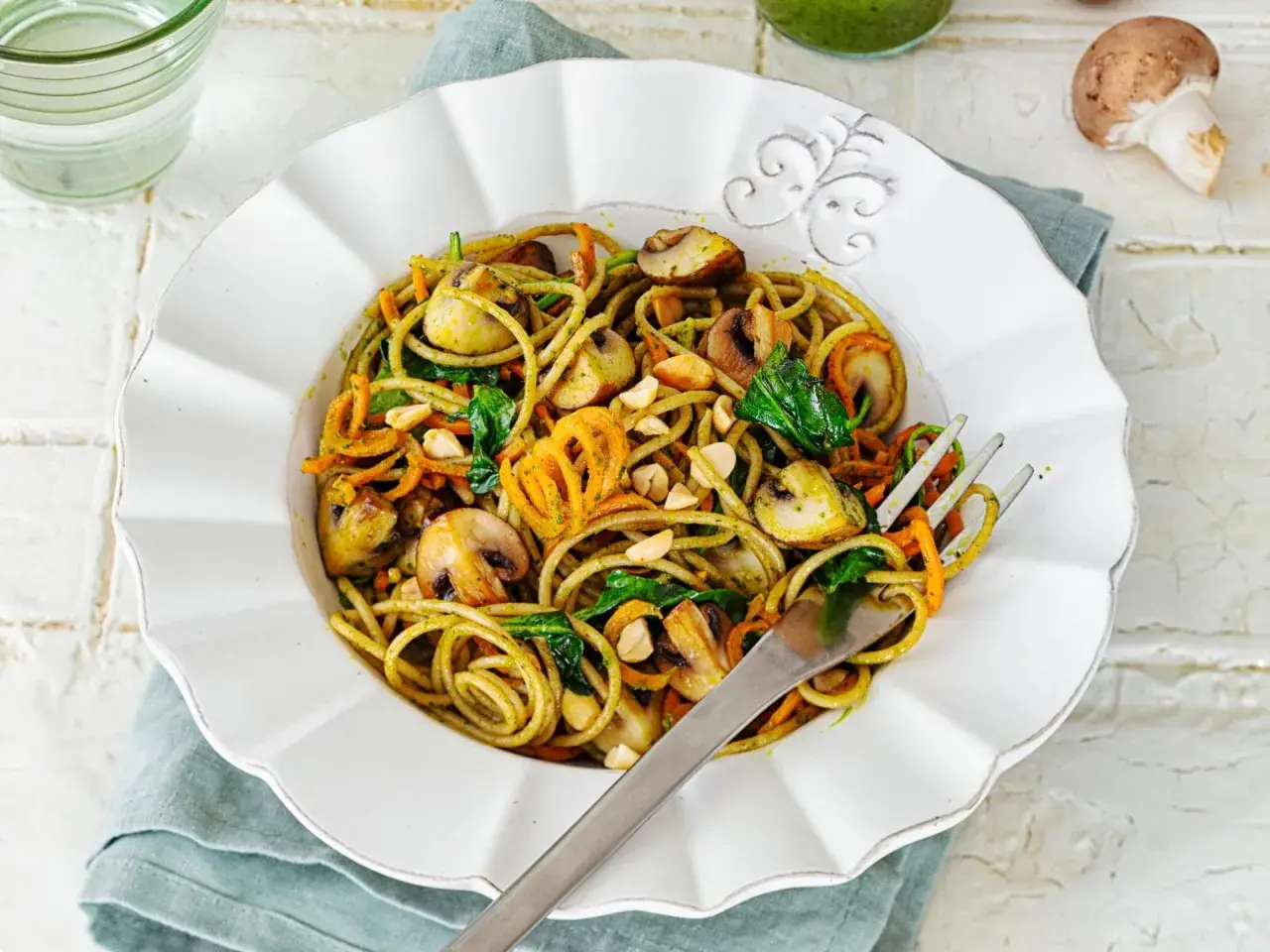 Leckere Spaghetti-Rezepte mit Pilzen, Karottenstreifen und Spinat, garniert mit Nüssen.