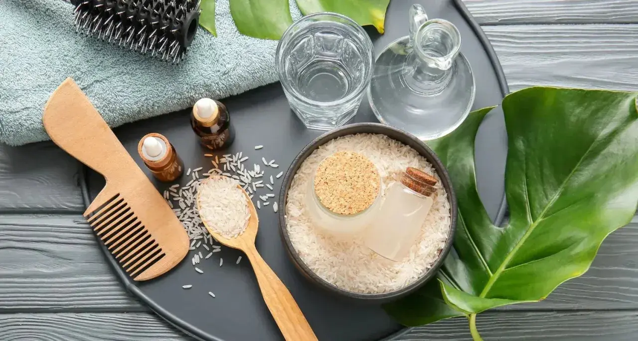 Ingredientes para el agua de arroz para el pelo: arroz, aceites, peine de madera, cepillo y toalla.
